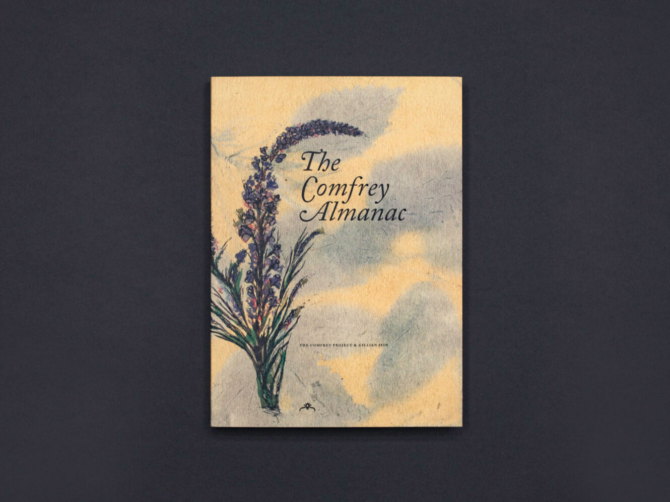 A colour photograph of The Comfrey Almanac publication on a black background